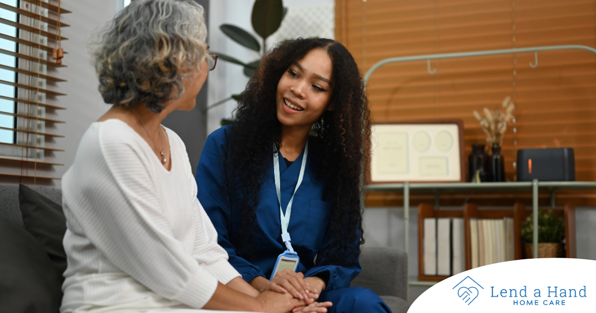 A caregiver patiently and kindly sits down and talks with a senior client, setting a good example for caregivers when it comes to communication.