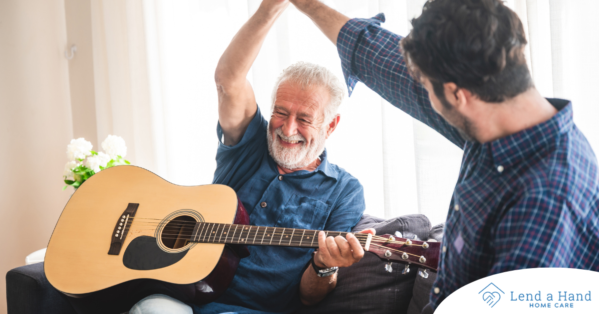 A smiling son high fives his happy elderly father as he plays the guitar, showing the positive effect music can have on people, including those with dementia.