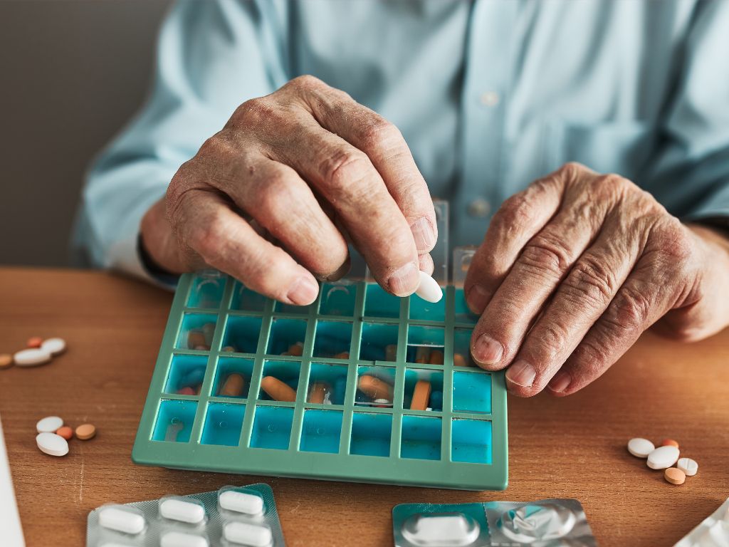 A senior putting pills into an organizer represents medication supervision in Reno.