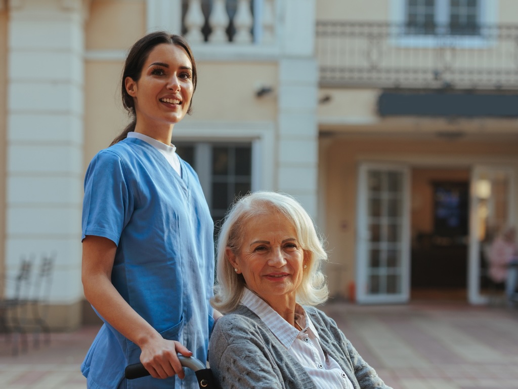 A caregiver helps a happy client, representing the effect that light housekeeping in Reno can have.