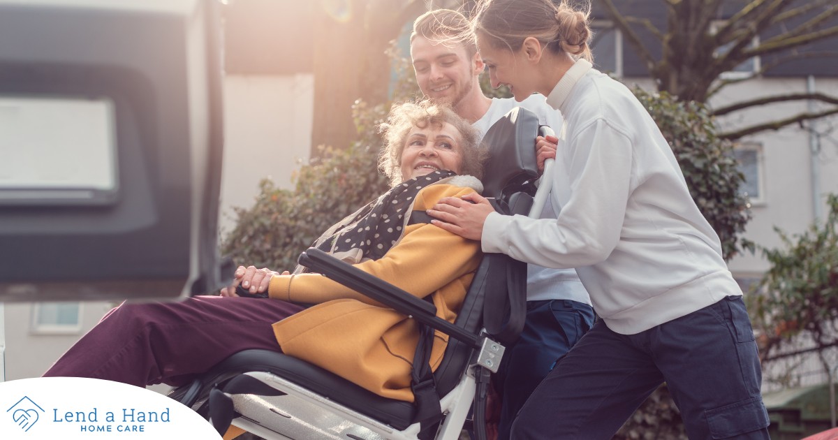 2 caregivers help an older adult get into a vehicle using a ramp, showing how equipment is valuable to professional caregivers when helping older adults.