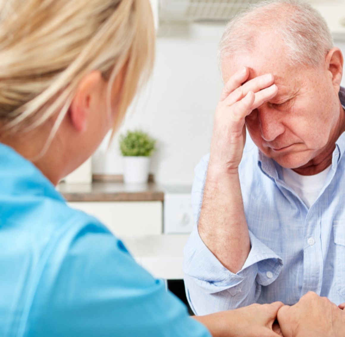Alzheimer’s and Dementia Care in Sun Valley (1) A man holding his head in pain as he talks to a care giver. Alzheimer's and Dementia Care in Sun Valley