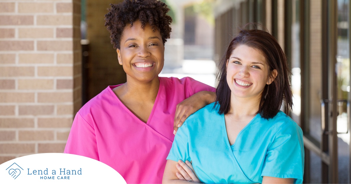 2 caregivers smile representing the good attitude that can allow home care professionals to collaborate.